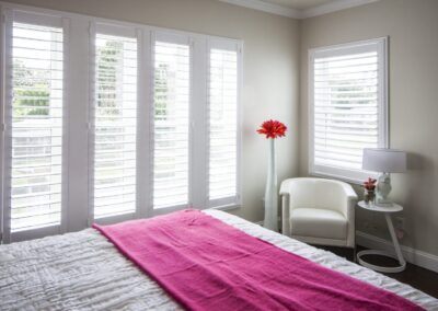 Sunlit bedroom with pink throw and shutters
